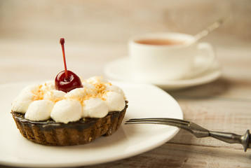 Cake with a cherry and white cup on the table