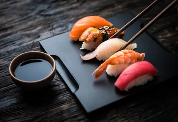 Fototapete Sushi-bar Nahaufnahme von Sashimi-Sushi-Set mit Stäbchen und Soja auf schwarzem Hintergrund