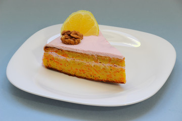 Sweet homemade carrot cake. Close up carrot cake with whipped frosting. Healthy carrot cake. Slice of carrot cake with walnuts and lemon. Homemade sponge cake on white plate. Shallow depth of field.