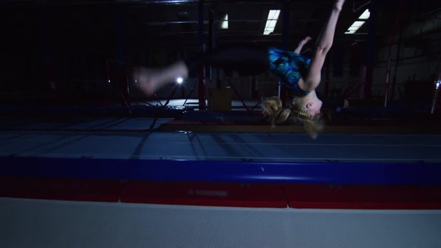  Professional female gymnast practicing flips on trampoline