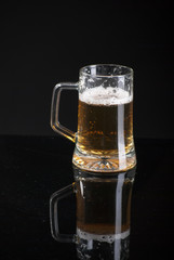 Beer glass with background and shinny reflection on bottom with beer falling into glass