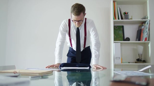  Young businessman pushing papers across desk in a confrontational manner