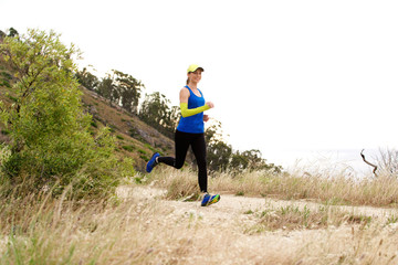 Sporty woman running on trail outdoors in baseball cap