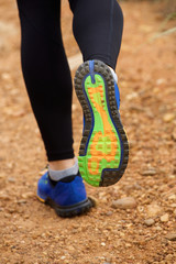 Fototapeta na wymiar Close up of woman's sneakers running on dirt road