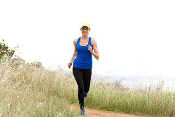 Smiling woman running on dirt path in nature