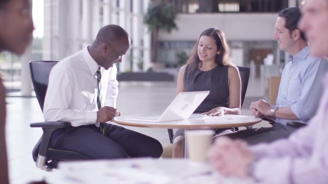  Mixed ethnicity business group chatting in large modern office building