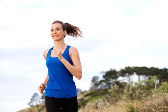 Smiling woman running outdoors in sportswear