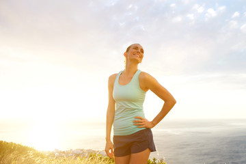 Smiling active woman standing outside during sunset