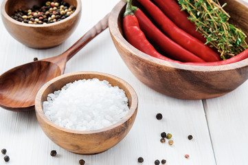 Salt, pepper, chili and thyme in bowls on white rustic wooden table