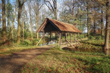 Bridge with the roof laid over a canal in the park.