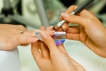 manicurist makes escalating of nails. Use the nail file makes nail shape. Hands shot close-up on a light background