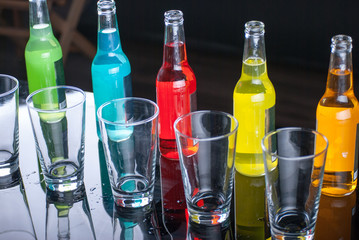 Jouice - soda transparent Glass and rainbow colored drinks bottles with black background