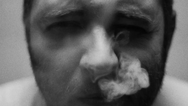 SUPER 35MM CAMERA - Young man smoking a cigarette. Black and white - grain and noise added for the effect.
