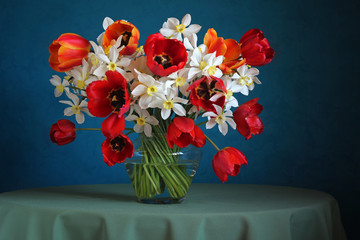 Obrazy na Szkle  Martwa natura z bukietem żonkili i tulipanów na niebieskim grzbiecie