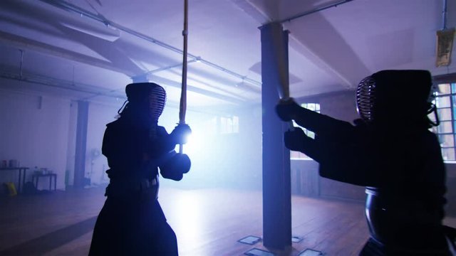  Japanese kendo fighters with bamboo swords competing in dark building