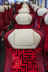Bus seats in row with red leather, textile coating and white headrests, modern comfortable tourist...
