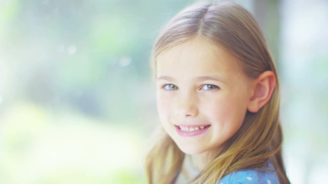  Portrait of pretty smiling little girl sitting by a window.