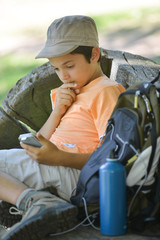 Fototapeta na wymiar Young boy seeking his path on a phone during a hike