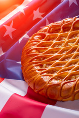 American flag and a pie. Pie laying on bright banner. Traditions of great country. Hospitality and peace.