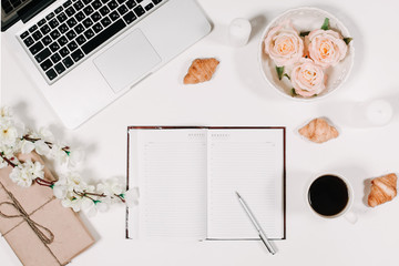 Workspace with diary, pen, vintage white tray, sakura, roses, croissants and coffee on white...