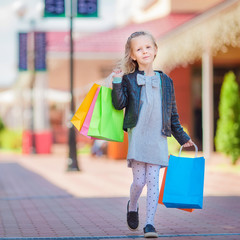 Adorable little girl walking with shopping bags outdoors