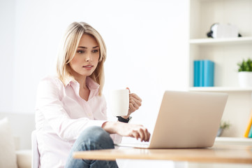 Cheerful blond girl is working on computer