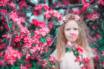 Naklejka premium Adorable little girl in a flowering spring apple garden