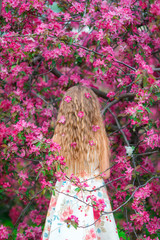 Adorable little girl enjoying smell in a flowering spring garden