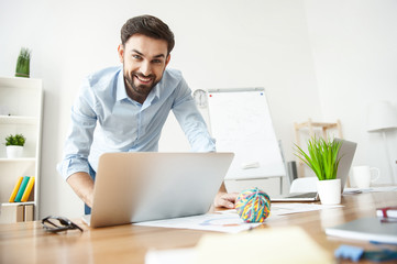 Cheerful man is using a notebook for work