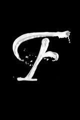 Obraz na płótnie Canvas Letter F made of milk, isolated on black