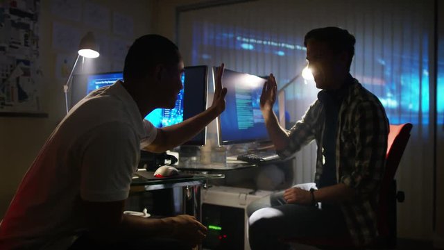  Young creative computer design team working together in dark office.