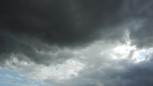 Zeitrafferaufnahme von hellen und sehr dunklen Wolken, die &uuml;ber den blauen Himmel ziehen 
