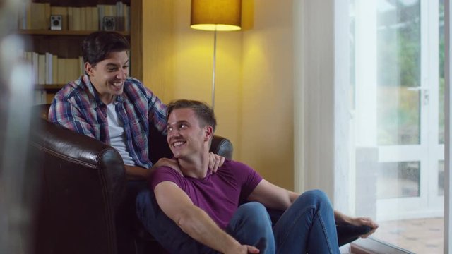 Attractive young gay couple relaxing at home and chatting
