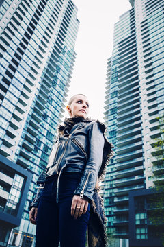 Wide angle low point of view, portrait of beautiful Caucasian white young bald girl woman with shaved hair head in leather jacket and scarf looking away, spiritual mood state of mind