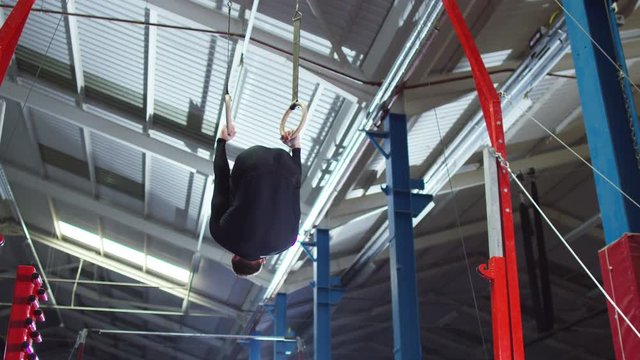  Professional male gymnast training on the rings at the gym. 