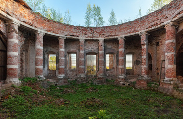 Ancient rotunda with columns without a dome. Abandoned brick temple overgrown with grass