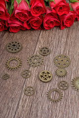 Obraz na płótnie Canvas Roses and gears on a wooden background