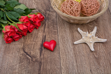 Starfish, heart and roses on a wooden background