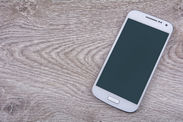 White mobile phone on a wooden background