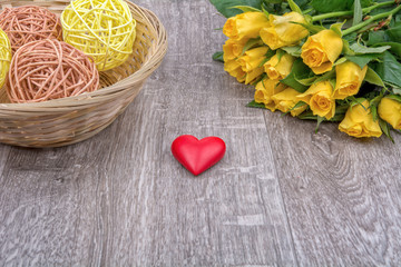 Yellow roses and heart on a wooden background