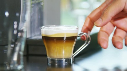 Hand reaches into shot to pick up a mug of fresh frothy coffee