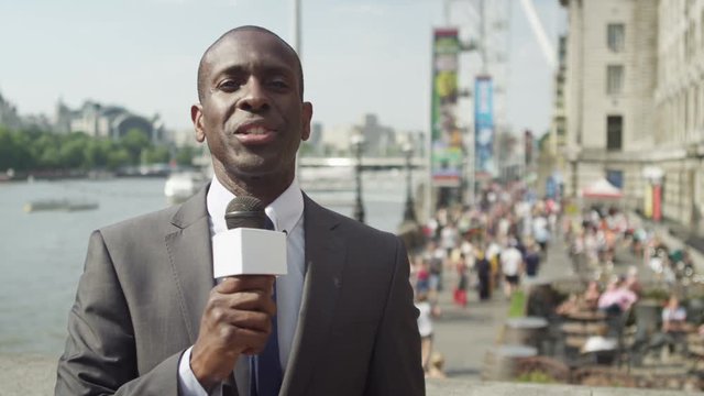  TV reporter doing live piece to camera outdoors in the city of London