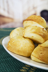 Fresh bread buns piled up, elegant white plate sitting on green table cloth, restaurant bakery concept