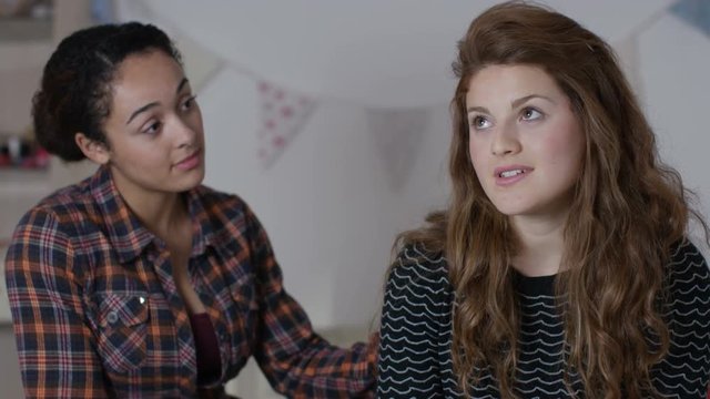  Teenage girls in bedroom, one girl tries to comfort her sad friend