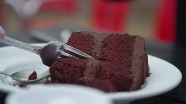  Close up beautiful Asian woman eating chocolate cake at outdoor cafe table