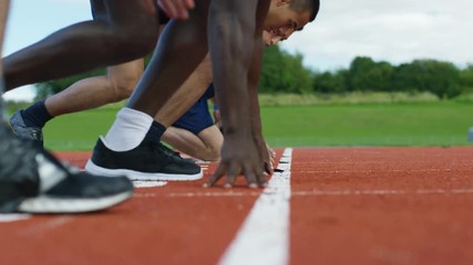  Group of athletes at running track, crouch at starting line before a race