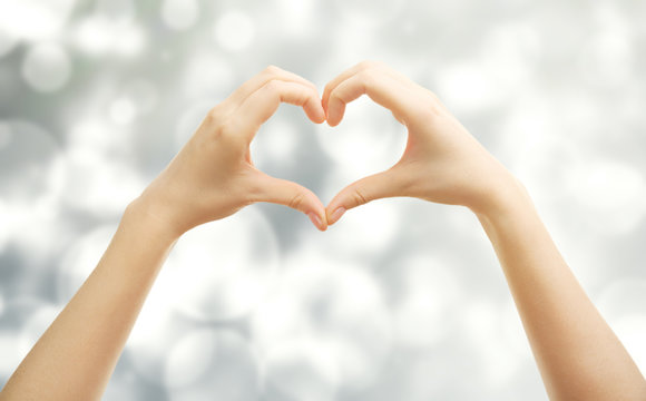 Female hands in shape of heart, on blurred background