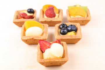 Assorted fruit tarts on wooden surface