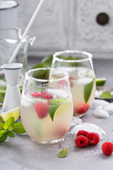 Cold summer cocktail with limes and raspberry