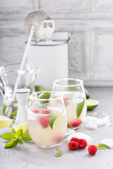 Cold summer cocktail with limes and raspberry